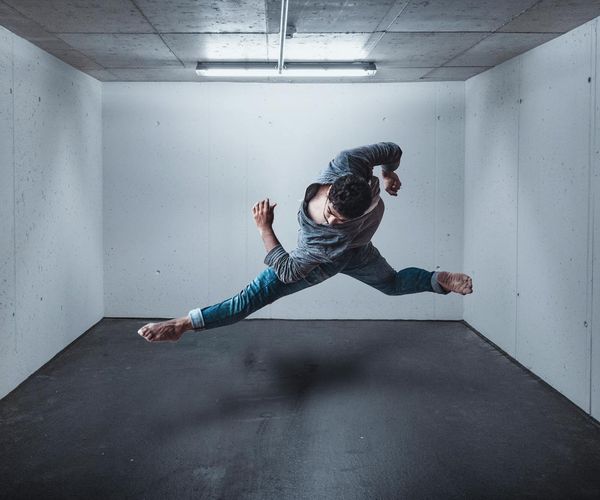 Man in a controlled strength pose in a brightly lit, modern space.