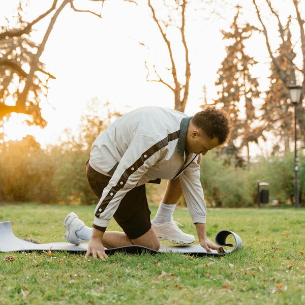 Man stretching outdoors with a serene natural background at sunrise.